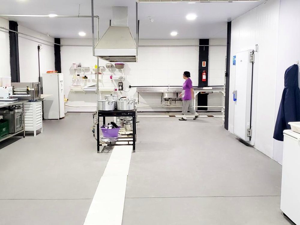 Área de produção da Chef di Animale, com fluxo demarcado e câmara frigorífica